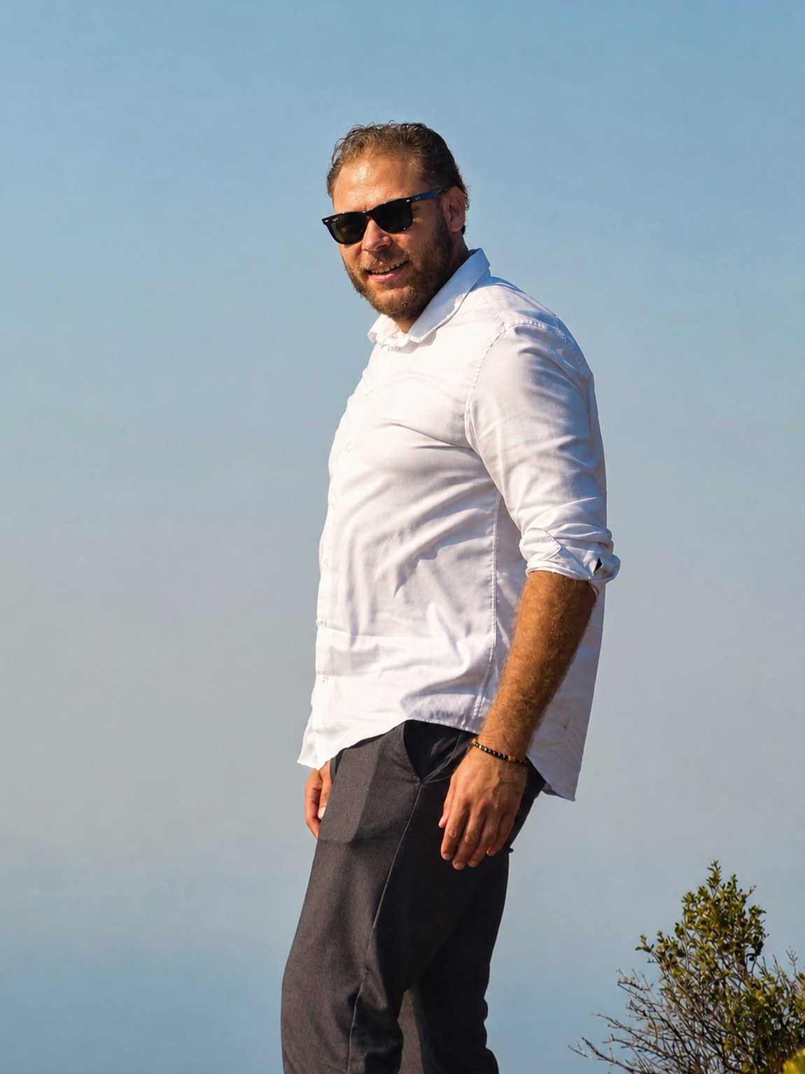 Maxime Mambert, chemise blanche, sur une hauteur au-dessus de la baie